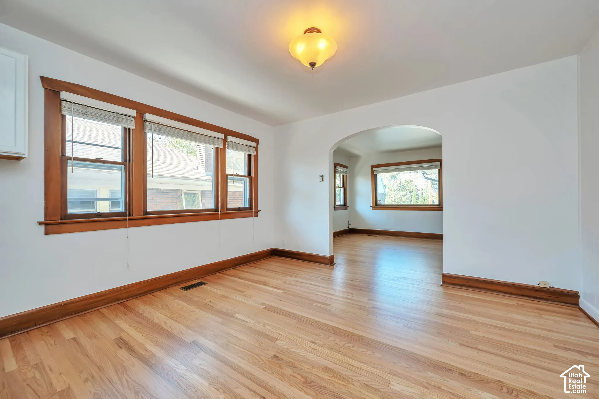 Hardwood flooring, arched doorway into living room wood-trimmed windows