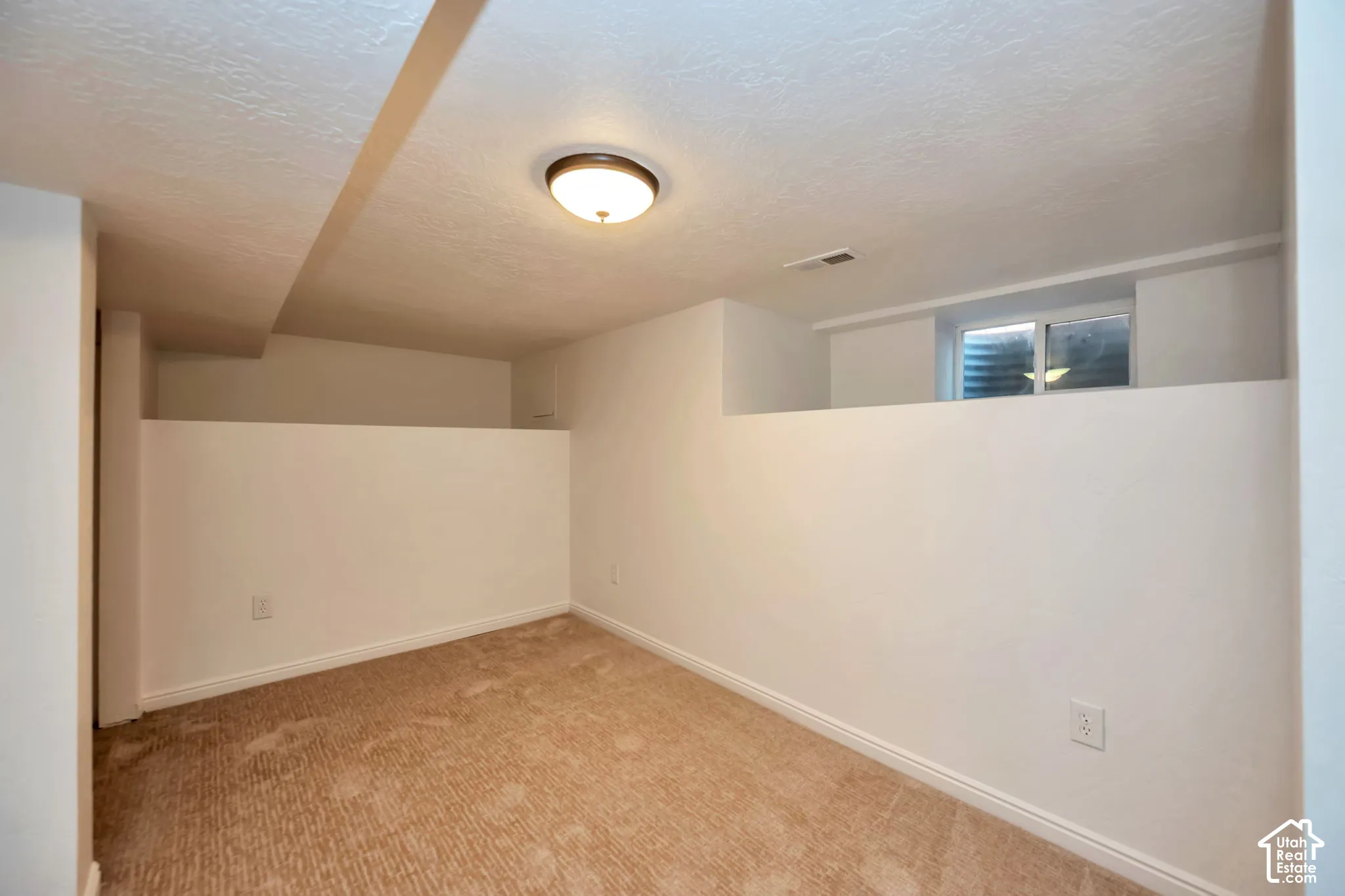 Carpeted flooring, egress window, white walls, and flush mount lighting
