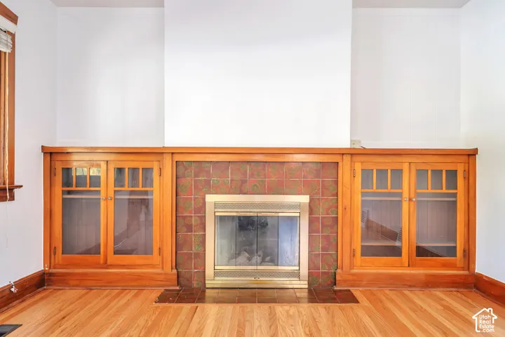 Built-in fireplace featuring a brass surround, brick-style tile, and gum wood-finish cabinetry with glass doors