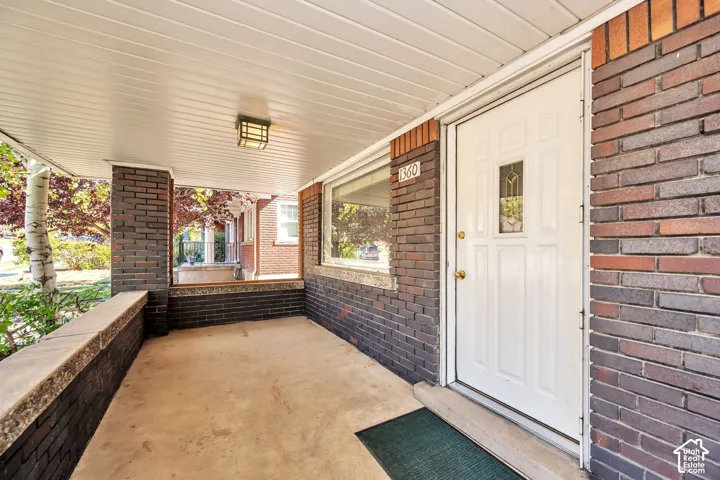 Large covered porch, concrete flooring, entry door with an ornamental glass insert