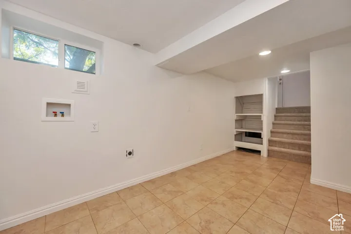 Entry to basement with tiled flooring, built-in shelving, recessed lighting, and a laundry hookups