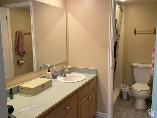 Bathroom featuring a wood-finish vanity with a single basin sink and a large wall-mounted mirror