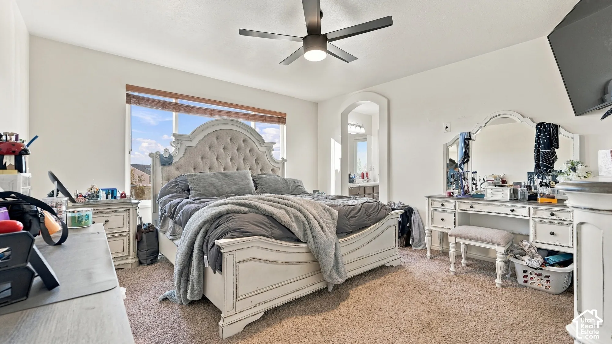 Recessed archway with interior lighting, ceiling fan with integrated lighting, window with horizontal blinds, and carpet flooring