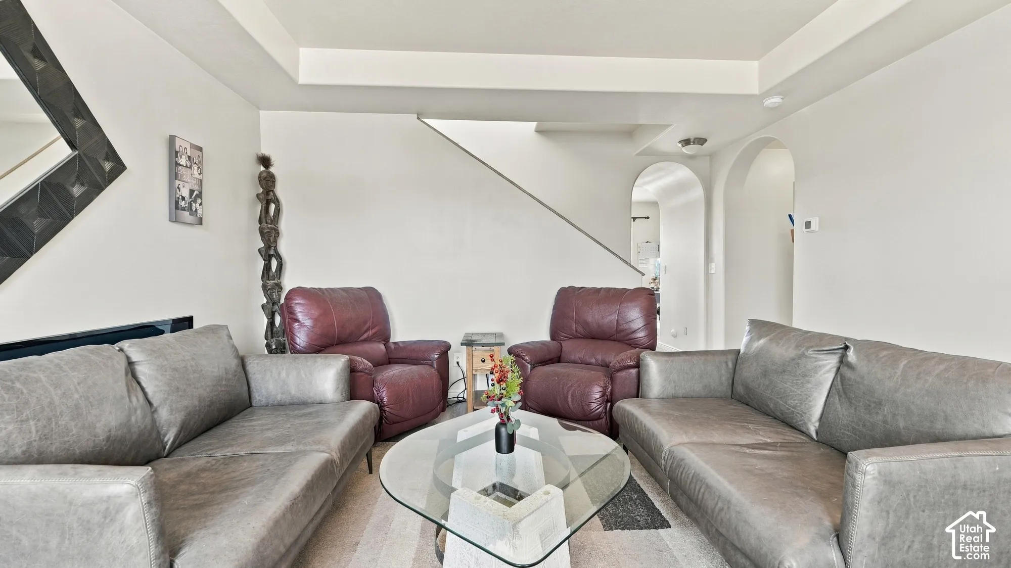 Archway openings, light wood-finish flooring, and a staircase with a metal railing