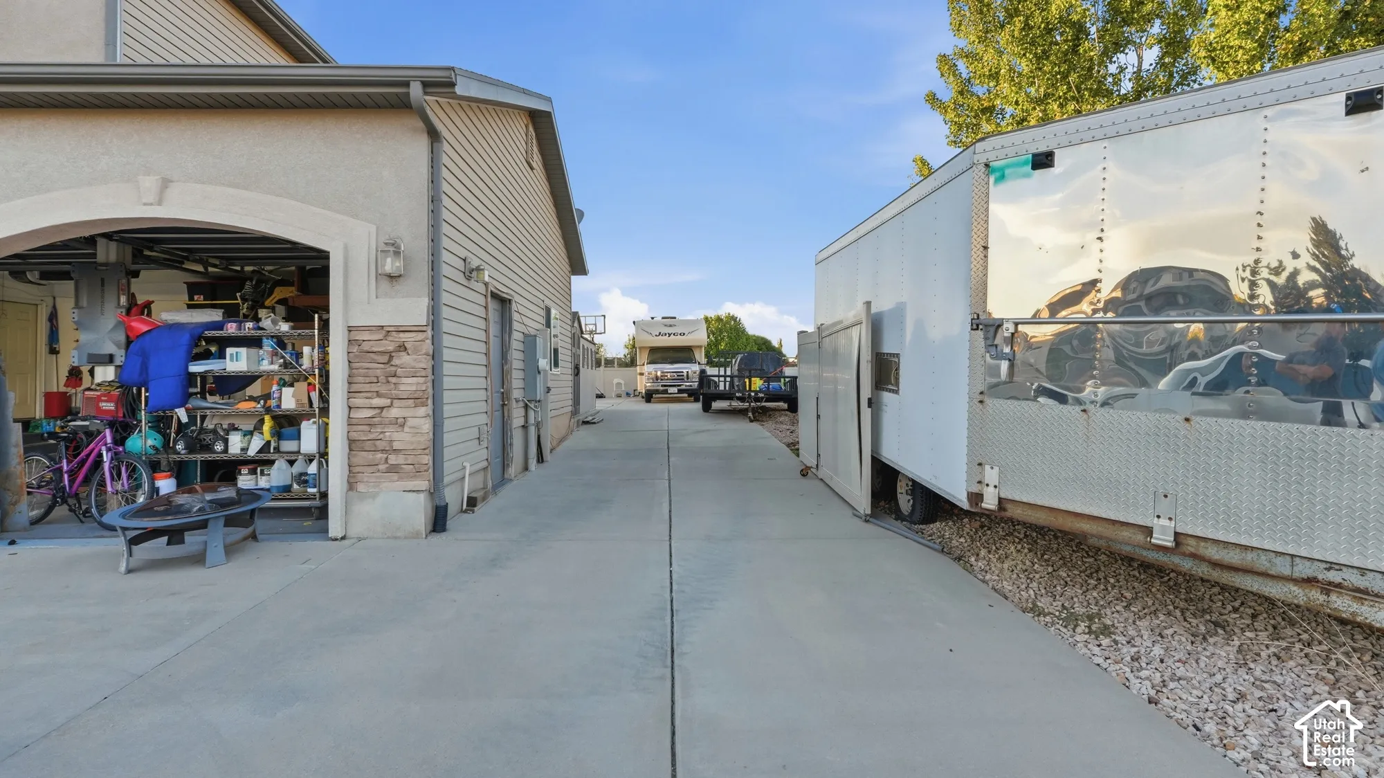 Concrete driveway with an attached garage featuring a stone accent wall and neutral siding