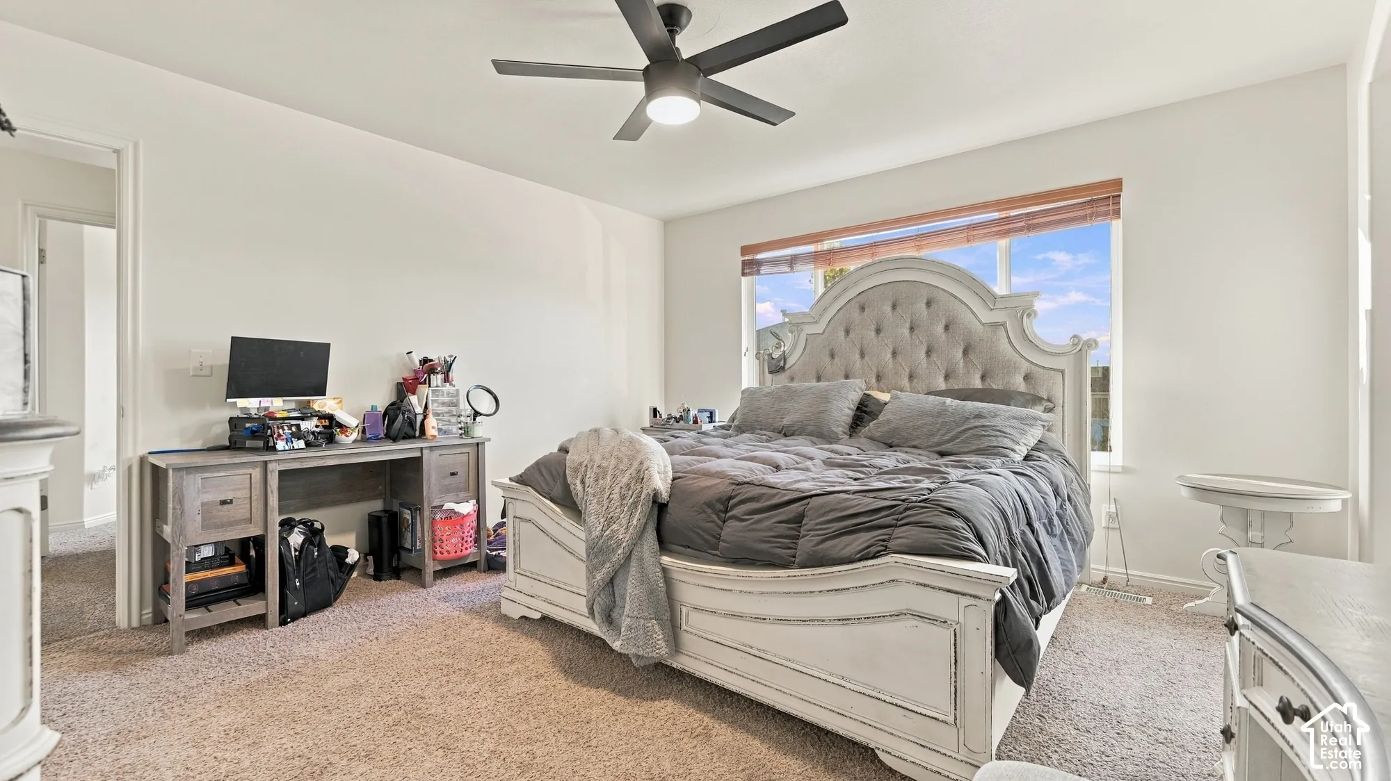 Expansive window with natural light, ceiling fan, and light-toned carpeting