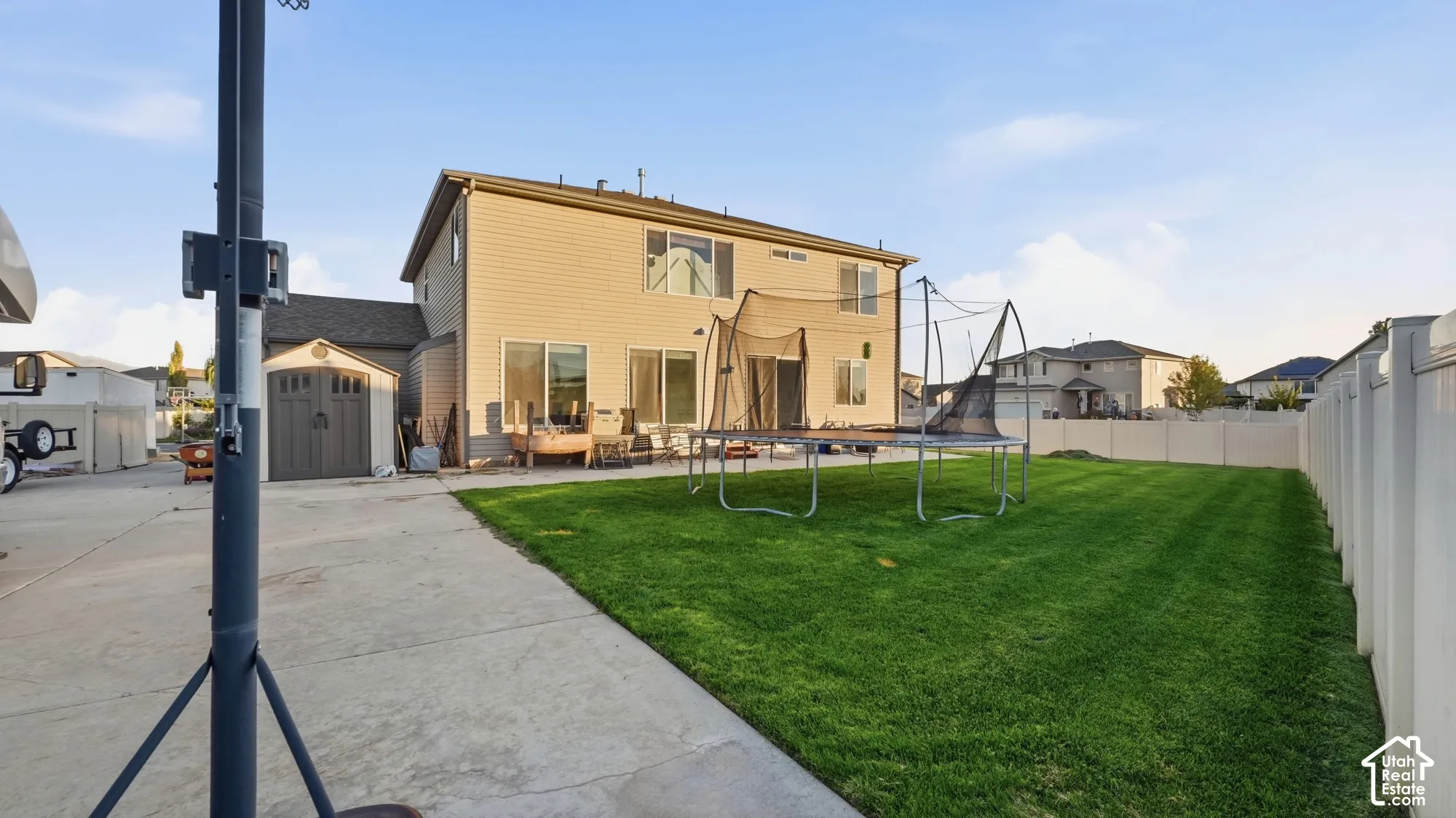 Expansive backyard featuring a manicured lawn, concrete patio area, and a private vinyl fence