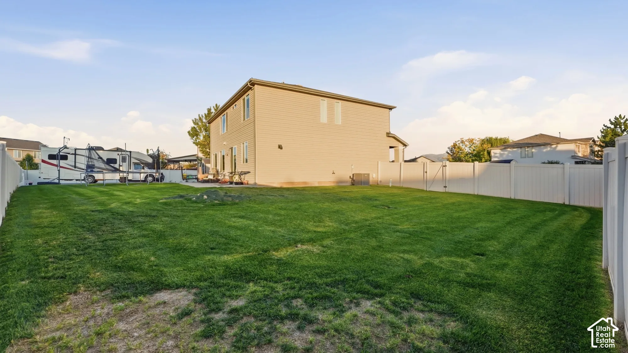 Expansive backyard featuring a manicured lawn, a full vinyl privacy fence, and a patio area
