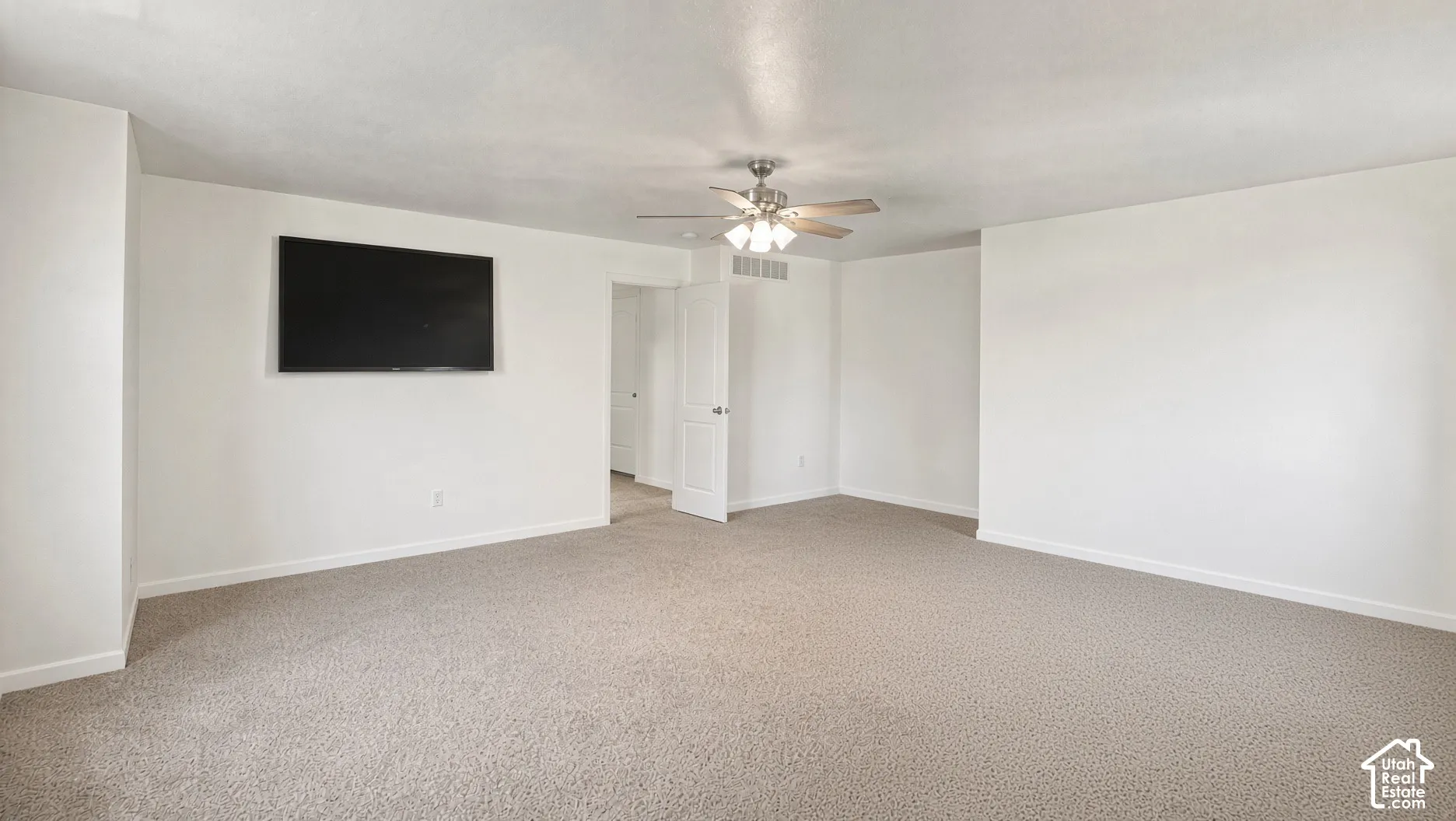 Neutral-toned carpeting, matte finish wall texture, and central ceiling fan with multi-light fixture