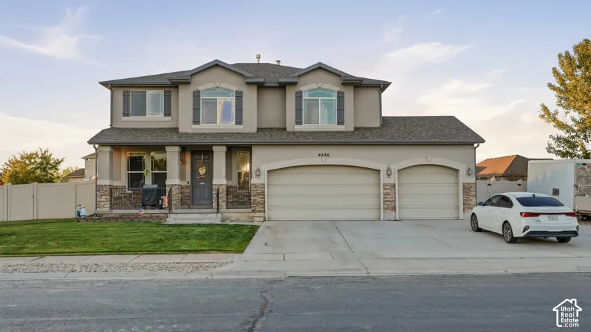 Two-story stucco exterior with stone accents, covered front porch, and a three-car garage