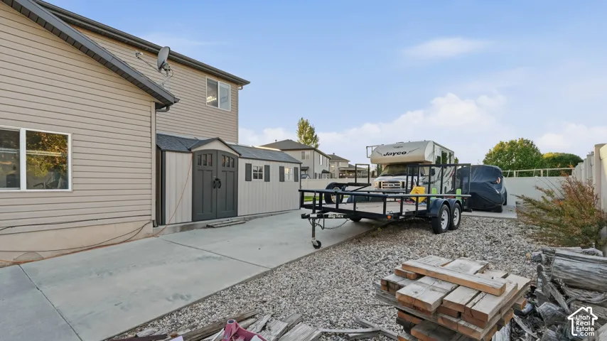 Concrete driveway leading to a gravel area with fencing