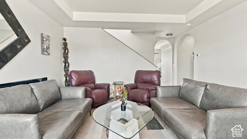 Archway openings, light wood-finish flooring, and a staircase with a metal railing