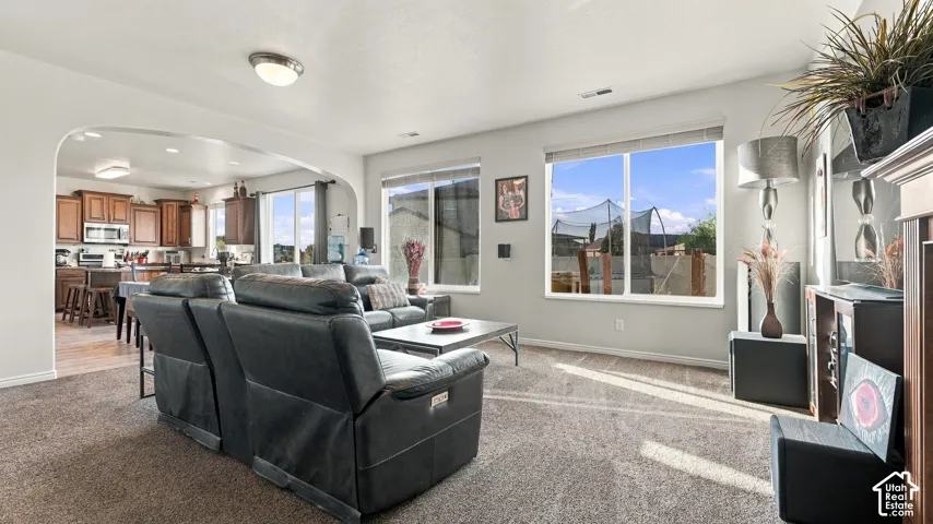 Open-concept living area with carpeting, light-colored walls, and ample natural light