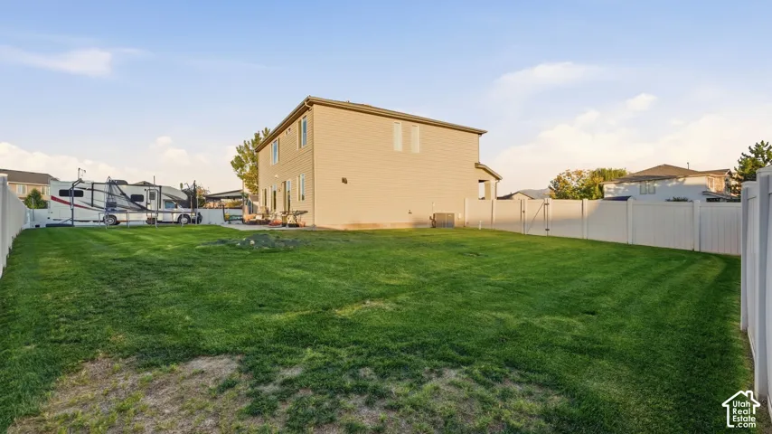 Expansive backyard featuring a manicured lawn, a full vinyl privacy fence, and a patio area