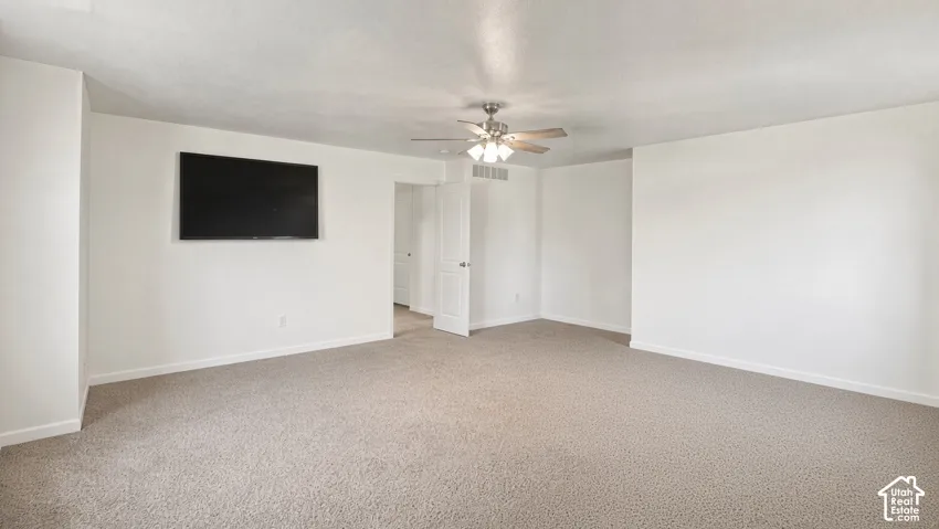Neutral-toned carpeting, matte finish wall texture, and central ceiling fan with multi-light fixture