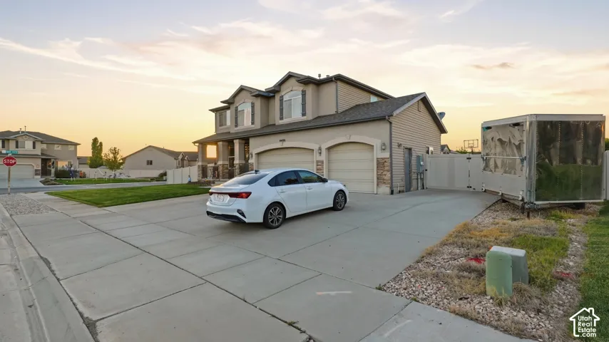 Two-story residence with a stucco and stone veneer exterior, featuring a two-car attached garage and a concrete driveway