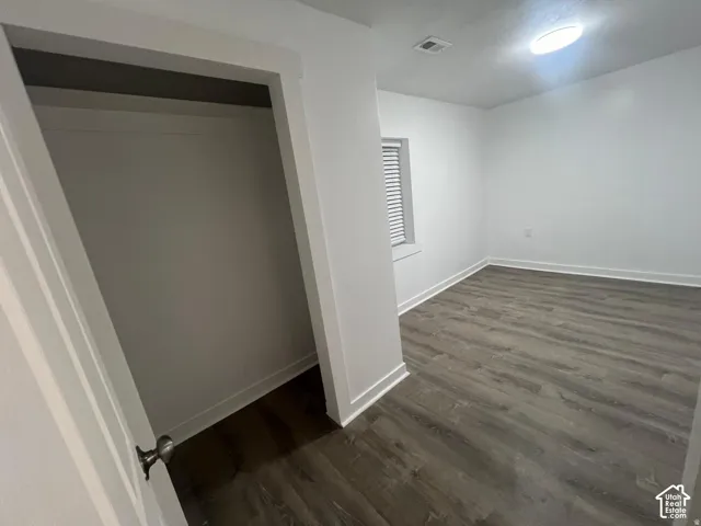 Light-filled room featuring wood-finish flooring, a window with horizontal blinds, and a flush-mount ceiling light