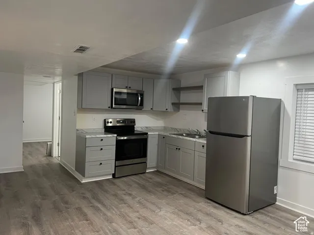 Kitchen featuring light gray cabinetry, stainless steel appliances, wood-finish flooring, recessed lighting, and a white countertop