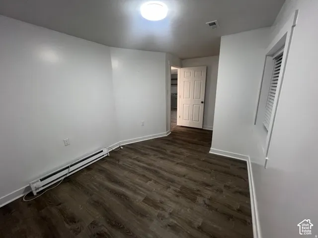 Wood-finish flooring, white walls, paneled interior door, and window with louvered blinds