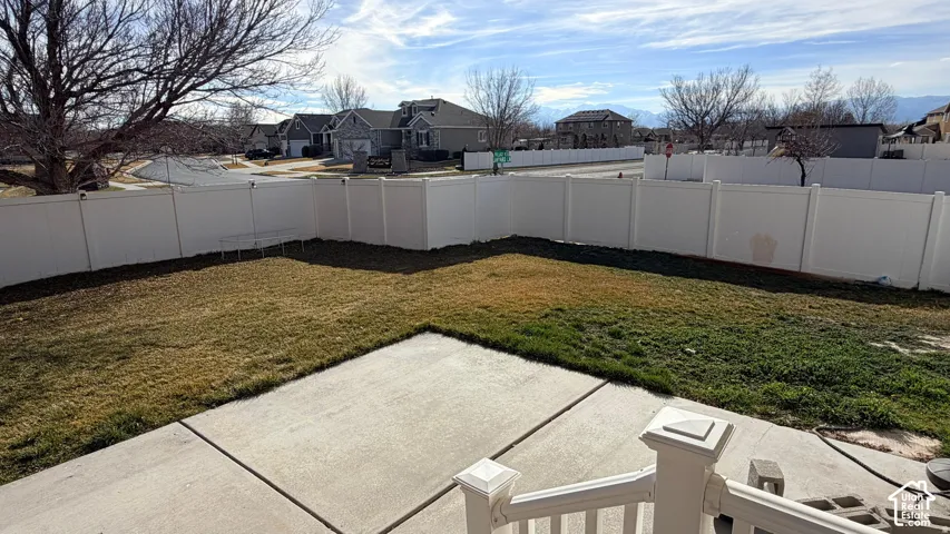 Expansive yard with concrete patio, enclosed by a white privacy fence