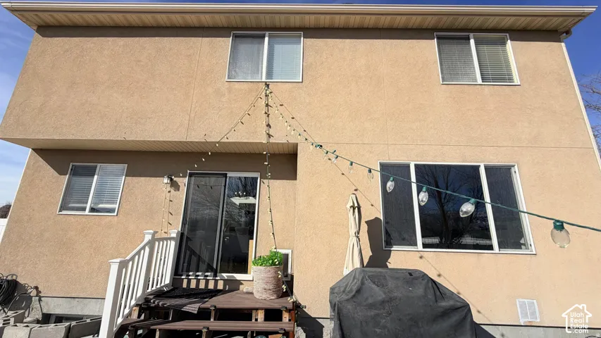 Stucco exterior with multiple windows, a sliding glass door, and white railing on a deck