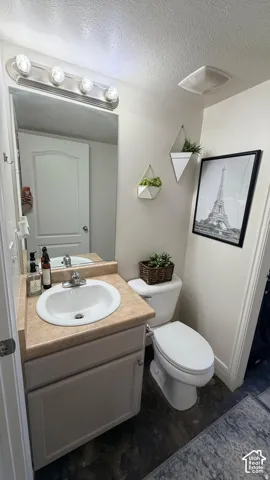 White vanity with an integrated sink, a light-toned countertop, and wood-finish flooring