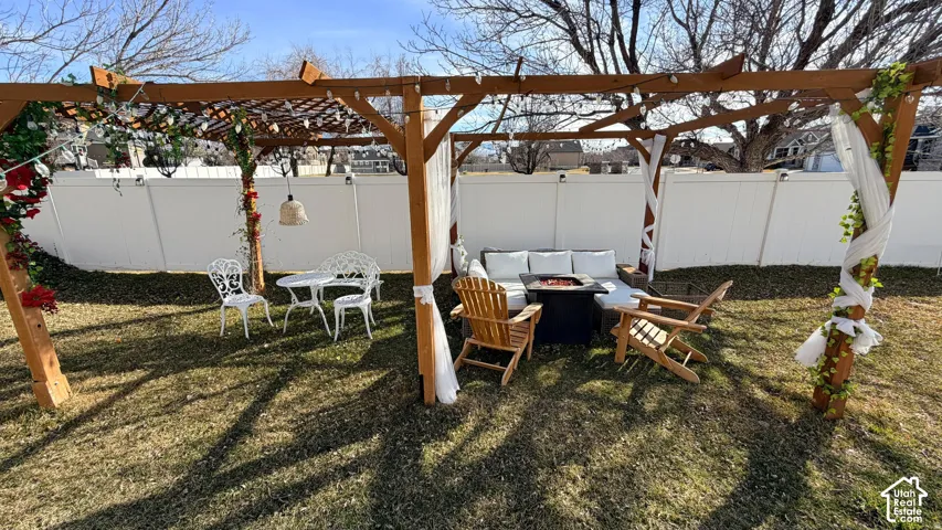 Expansive backyard oasis featuring a wood pergola structure with climbing vine accents, mature shade trees, and a manicured lawn