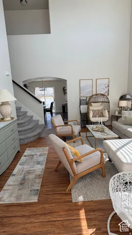 Vaulted ceiling, wood-finish flooring, curved staircase with carpeted treads, arched doorway, and built-in shelving