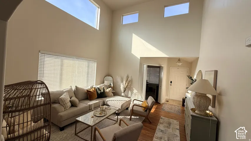 Vaulted ceilings with high windows, main-level windows with blinds, wood-finish flooring, recessed entry, and built-in entry light fixture