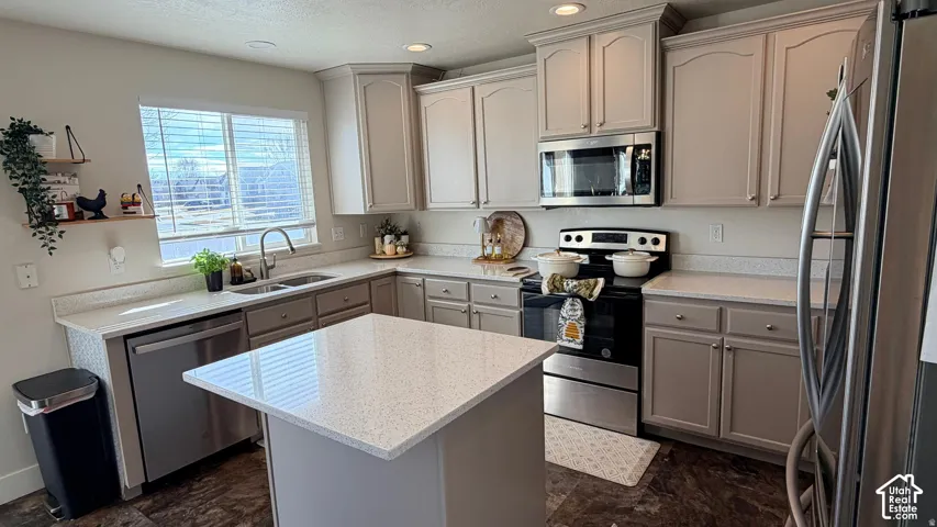 Contemporary kitchen featuring light gray cabinetry, stainless steel appliances, a center island with a light-toned countertop, and wood-finish flooring