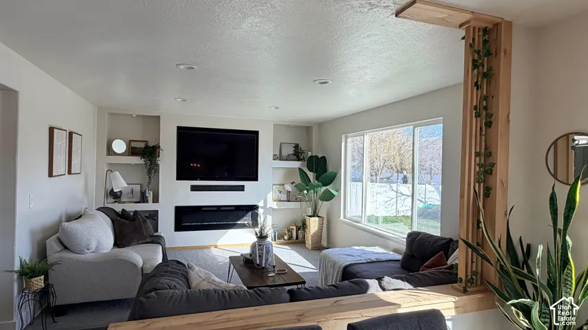 Recessed lighting illuminates a built-in media center with shelving and an integrated fireplace