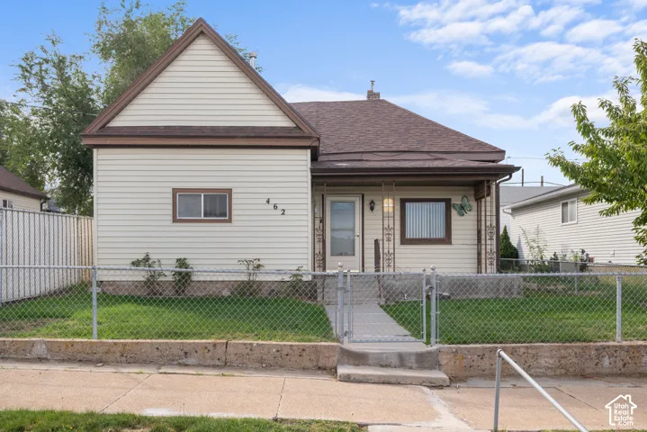 Siding exterior with a covered porch, chain link fence, and a concrete pathway