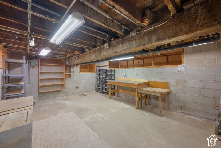 Concrete block walls with exposed wood beam ceiling, featuring built-in wooden shelving and a dedicated workspace