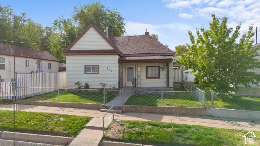 Siding exterior with a gable roofline, featuring a covered front porch and a chain-link fence