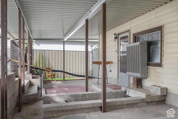 Covered patio with corrugated metal roofing, multiple support columns, and concrete flooring