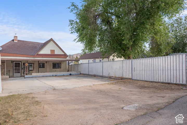 Single-story residence with a covered porch, an attached concrete patio, and a chain-link fence with privacy slats