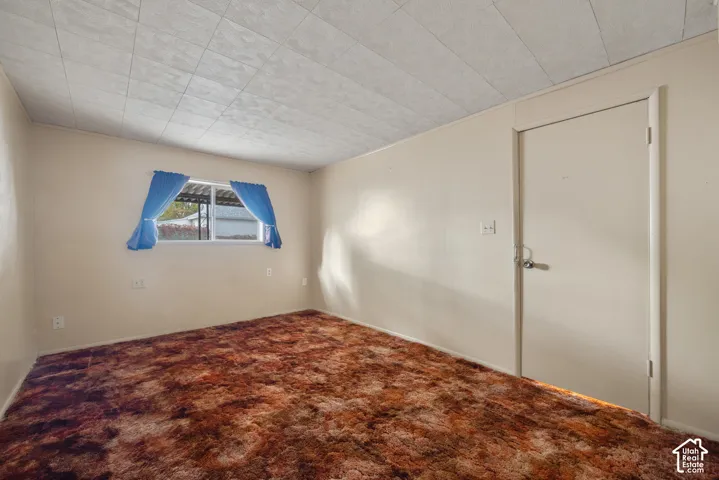 Textured ceiling tiles, wall-to-wall carpeting, and a white interior door with a silver-tone handle