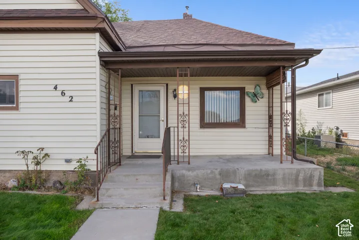 Covered front porch with decorative metal railings, concrete steps, and vinyl siding