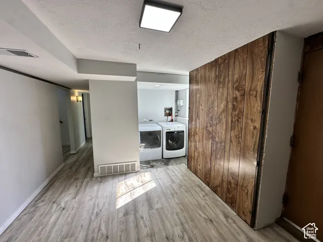 Laundry area featuring a front-loading washing machine, a front-loading dryer, and wood-finish flooring