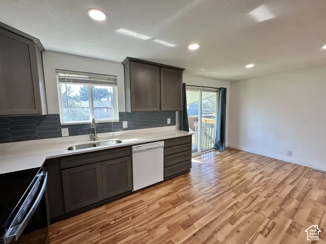 Wood-finish flooring, recessed lighting, dark cabinetry, light countertops, and a sliding glass door