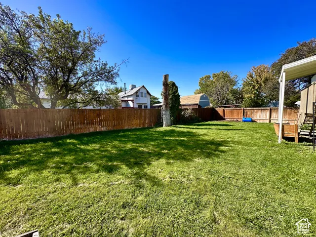 Expansive lawn with wood-panel fencing and mature trees