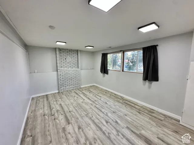 Painted brick feature wall, wood-finish flooring, multiple recessed lighting fixtures, and two windows