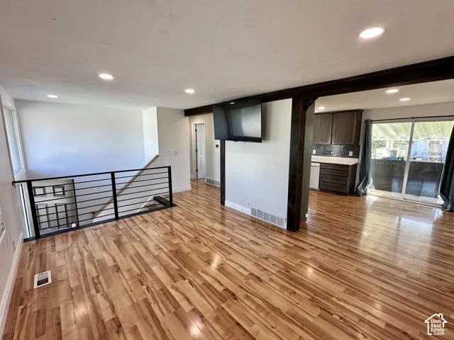 Wood-finish flooring throughout, recessed lighting, and a modern horizontal bar railing