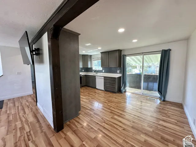 Wood-finish flooring throughout, recessed lighting, sliding glass door, and dark wood beam accents