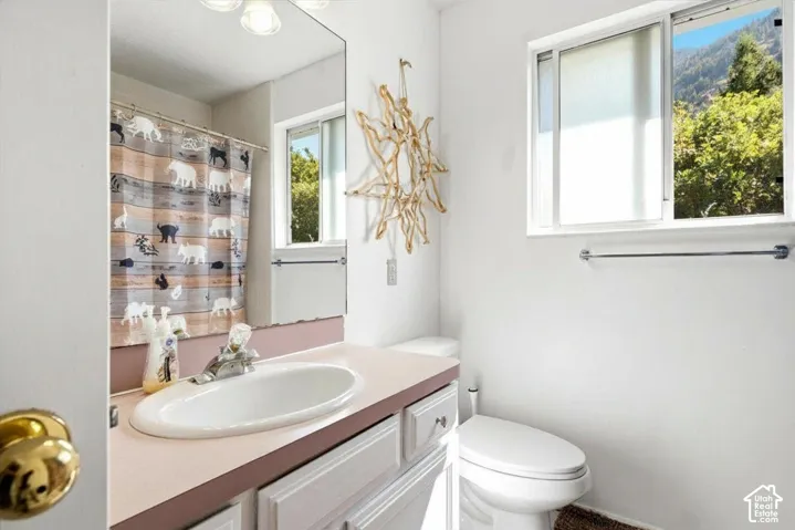 White vanity with integrated sink and pink countertop, wall-mounted mirror, and sliding window