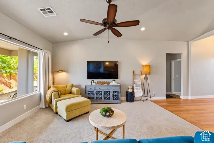 Vaulted ceiling with a ceiling fan, recessed lighting, large window, and wood-finish flooring