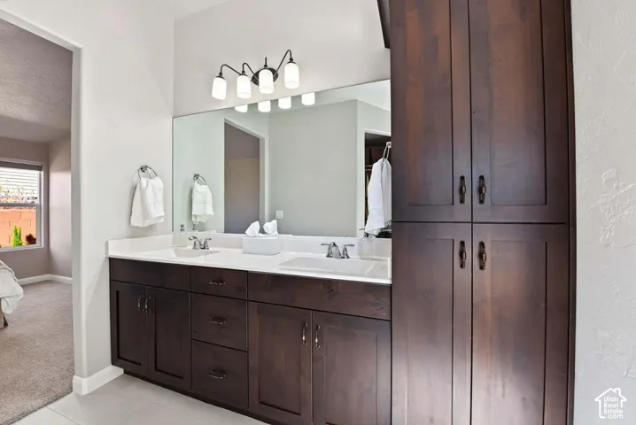 Dual vanity with undermount sinks, white countertop, dark wood-finish cabinetry, and built-in vertical storage