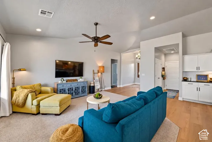 Recessed ceiling lighting, vaulted ceiling, wood-finish flooring, ceiling fan, and built-in cabinetry with dark countertops