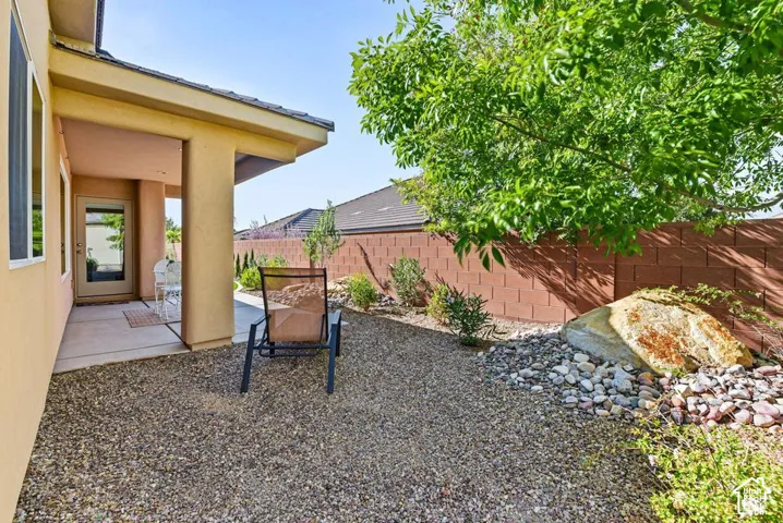 Covered patio with exterior access, gravel landscaping, and a privacy wall