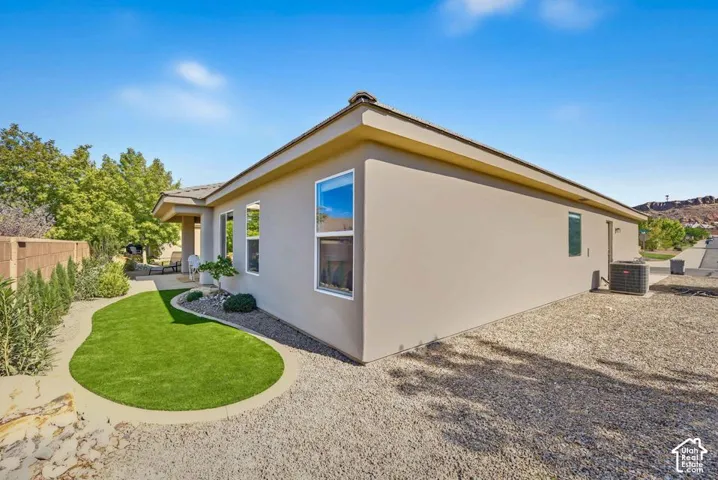 Stucco exterior with multiple windows, air conditioning unit, and gravel landscaping